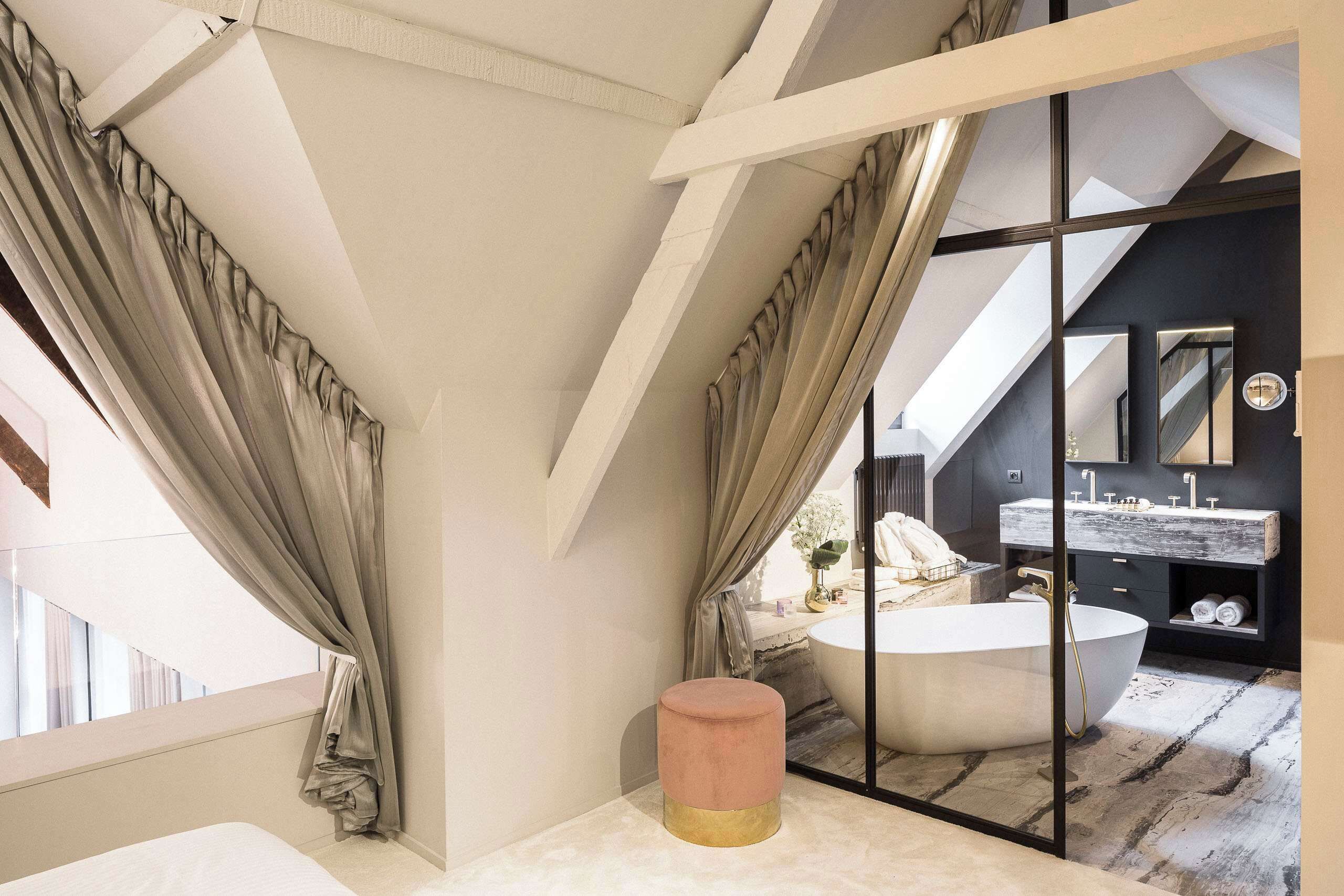 A modern bathroom with a large bathtub, a vanity with a mirror, and a window with curtains.
