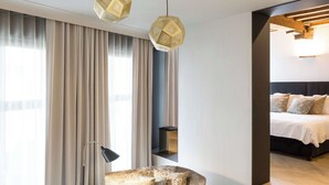 A modern hotel room with a large window, a comfortable armchair, a bedside table, and a neatly made bed. - Secret & private suite with timeless elegance (Antwerpen)