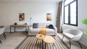 Un saló modern amb un sofà, dues taules laterals, un escriptori i obres d'art a les parets.