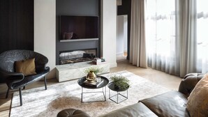 Un salon moderne avec une cheminée, un canapé, une table basse et un téléviseur fixé au mur.