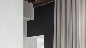 Un couloir avec un mur blanc, un mur foncé et un rideau blanc.