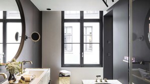 Une salle de bain moderne dotée d’une grande fenêtre, d’une baignoire et d’un meuble-lavabo avec un miroir.