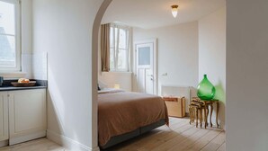 A bedroom with a bed, a radiator, a window, and a green vase on a side table. - Cozy Hideaway Near the Heart of Antwerp (Antwerpen)