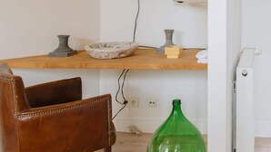 A room with a wooden desk, a leather chair, a green glass bottle, a flat-screen TV mounted on the wall, and a white radiator. - Cozy Hideaway Near the Heart of Antwerp (Antwerpen)