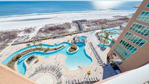 Un resort con una amplia zona de piscina, una playa y vistas al océano.