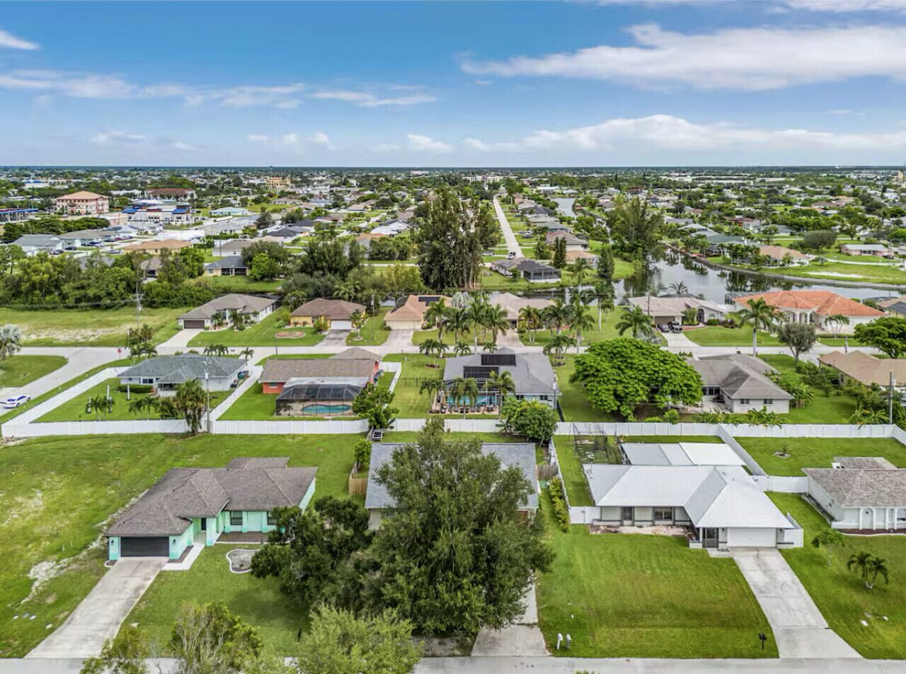 Vue aérienne d’un quartier résidentiel avec des maisons, des pelouses verdoyantes et des arbres.