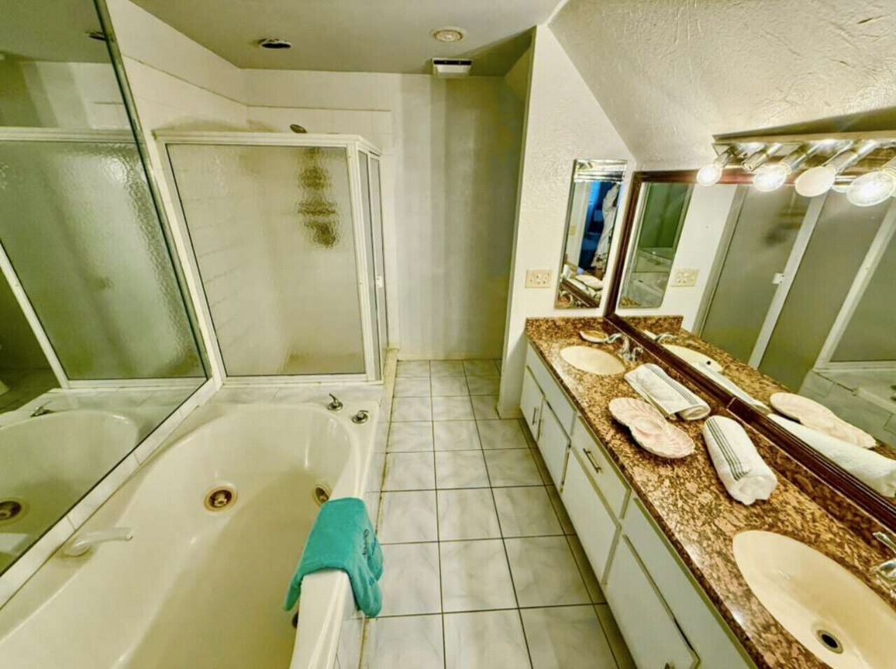 A bathroom with a bathtub, two sinks, a shower, and a vanity with a mirror.