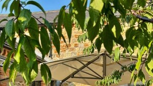 Un espace de restauration en plein air avec une table dressée pour six personnes, entouré de murs en briques et de plantes en pot.