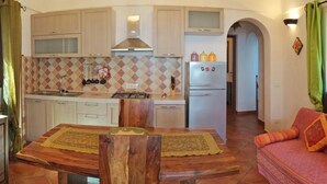 Cocina compacta con una mesa de comedor, un sofá y suelo de baldosas.