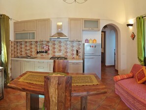 A compact kitchen with a dining table, a sofa, and a tiled floor. - Dammuso Gelso' Wohnung mit Blick aufs Wasser by Interhome (Pantelleria)
