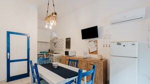 Eine kompakte Küche mit Essbereich, weißen Wänden, einem Flachbildfernseher und einem Kühlschrank.