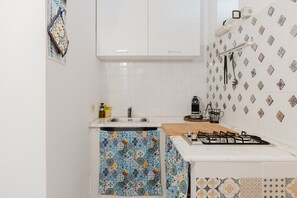 A kitchen with a sink, stove, and patterned tiles. - Apartment 'La Luna' with Private Terrace, Balcony and Air Conditioning (Castellammare del Golfo)