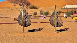 Paisagem desértica com uma tenda, uma mesa e um banco estampado.