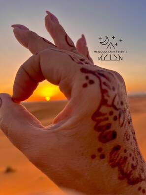 A hand with henna designs against a sunset backdrop. - Merzouga desert morocco (Merzouga)