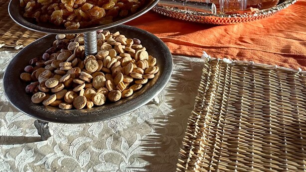 Área de refeições coberta com um buffet que oferece nozes, passas e uma cafeteira tradicional.