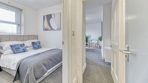 Une chambre à coucher avec un lit, un tableau et une vue sur la salle à manger.