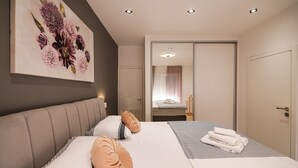 Ein modernes Hotelzimmer mit einem großen Bett, einer Kopfteil, einem Blumenbild und einem Badezimmer mit Spiegel sowie einer Tür.