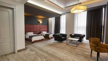 A hotel room with a large bed, two armchairs, a small table, and a sofa.