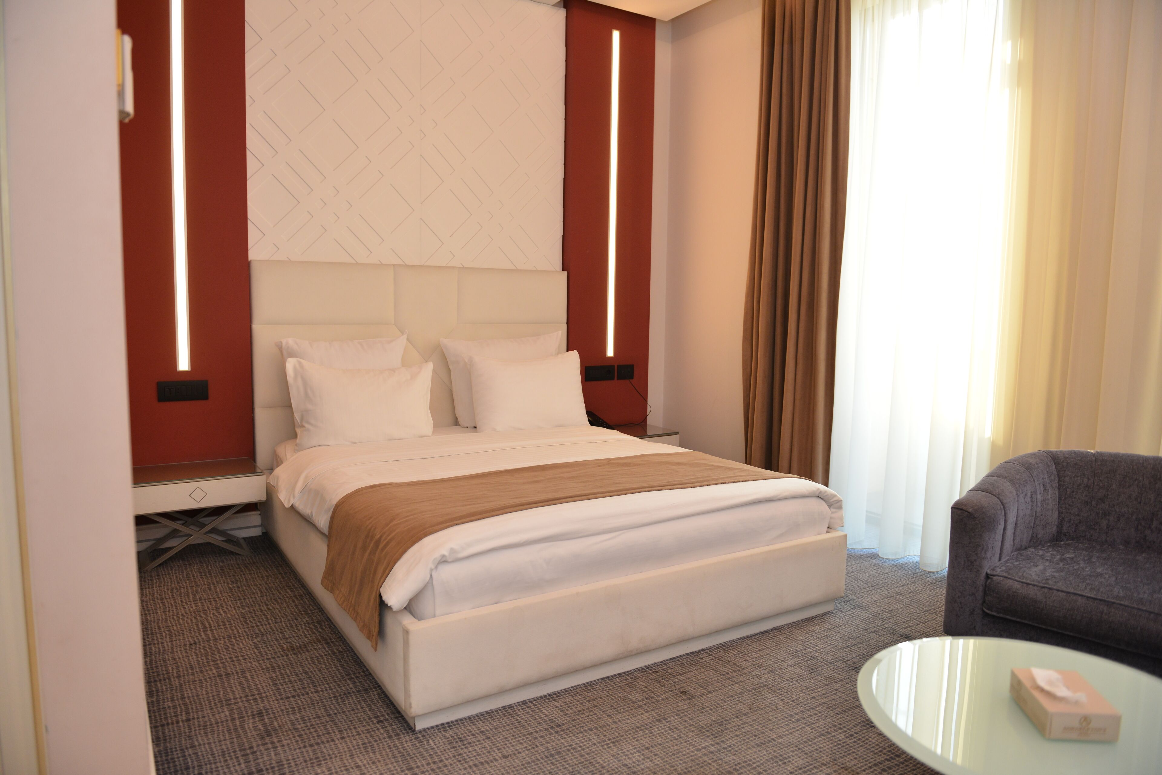 A hotel room with a bed, a sofa, a coffee table, and a window with curtains.