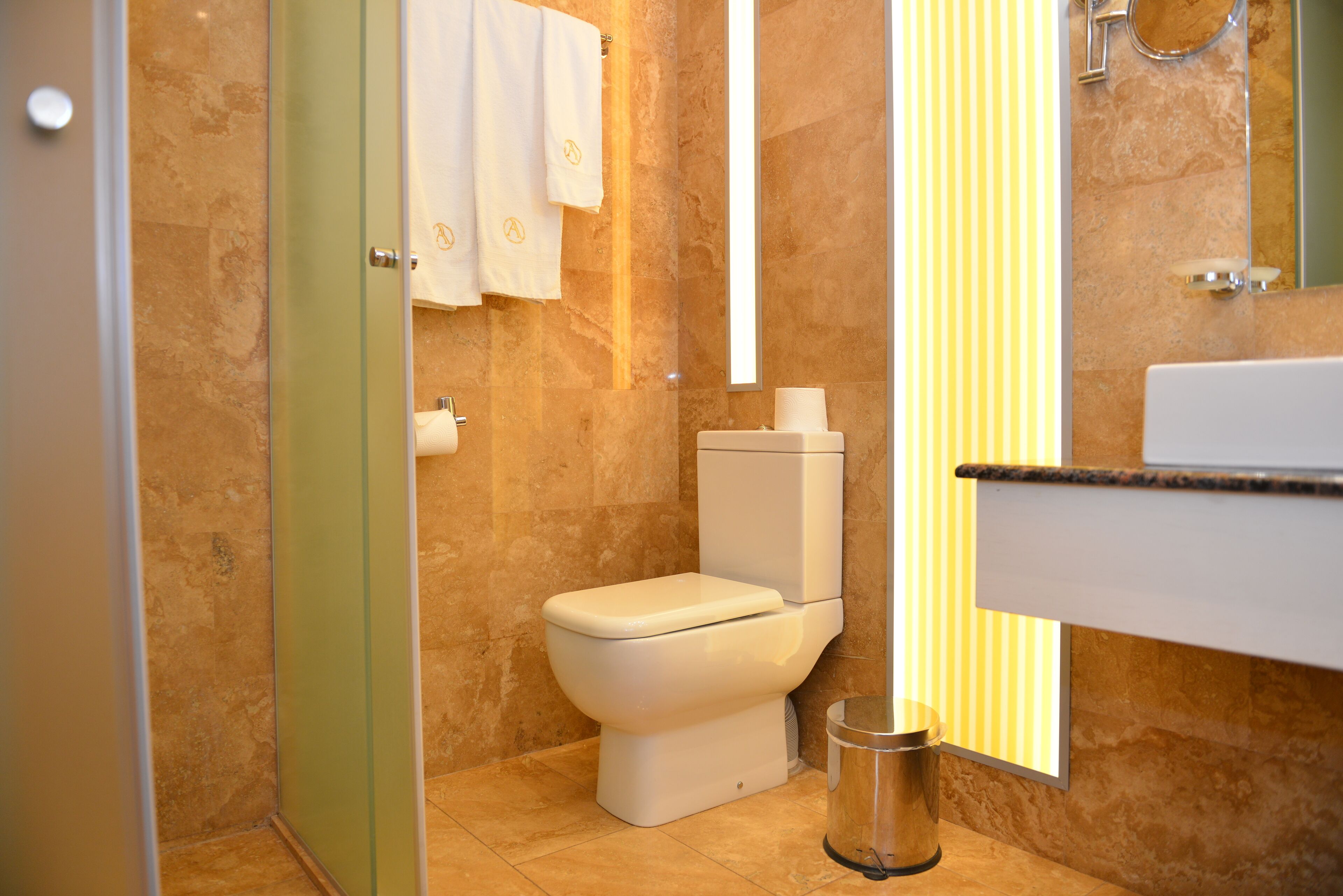 Une salle de bain moderne équipée de toilettes, d’une poubelle et d’un porte-serviettes.