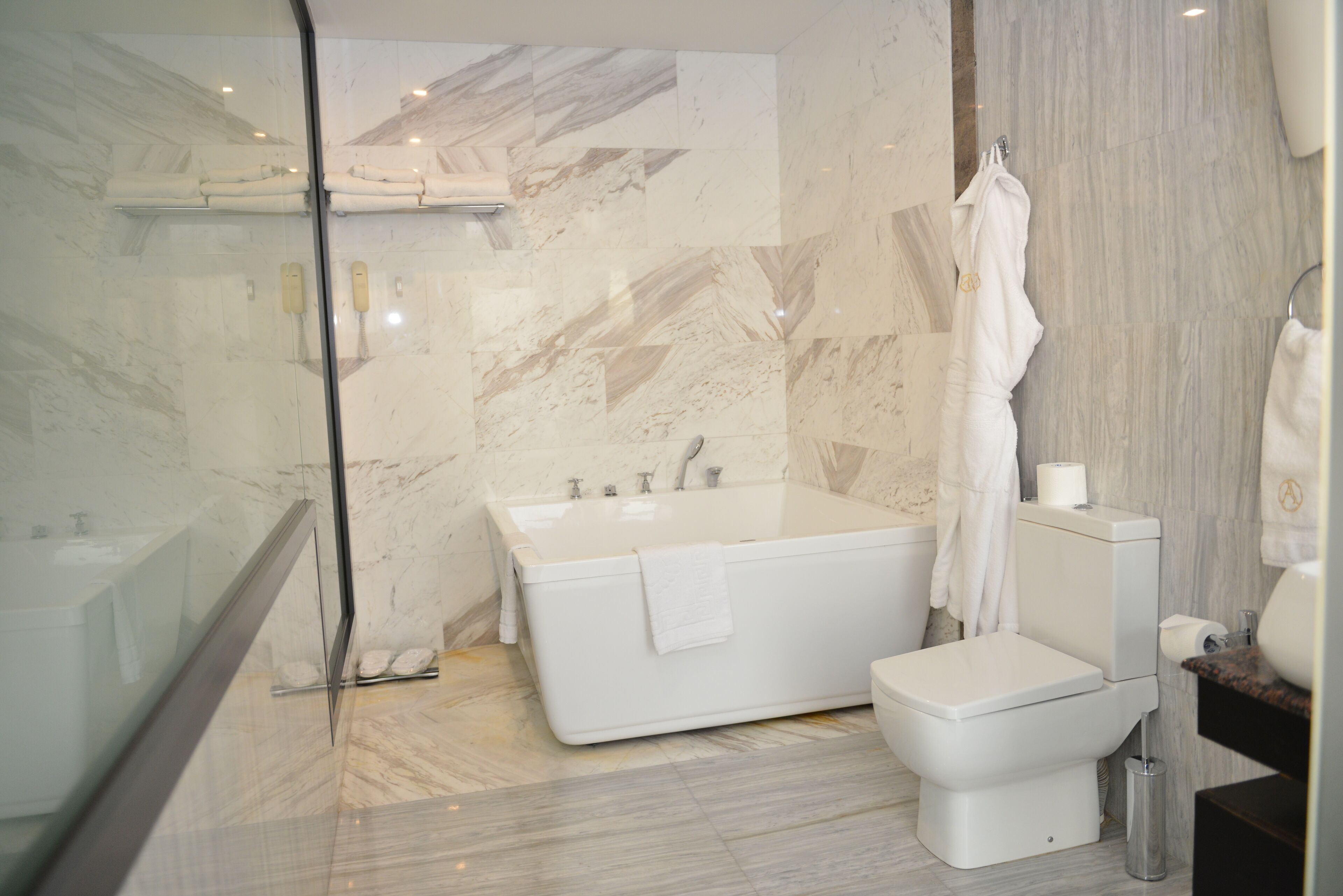 Ein modernes Badezimmer mit einer großen Badewanne, Toilette und einer Duschkabine aus Glas.