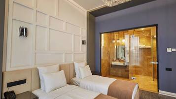 Quarto de hotel com duas camas, porta de madeira que dá para um banheiro e um candelabro.