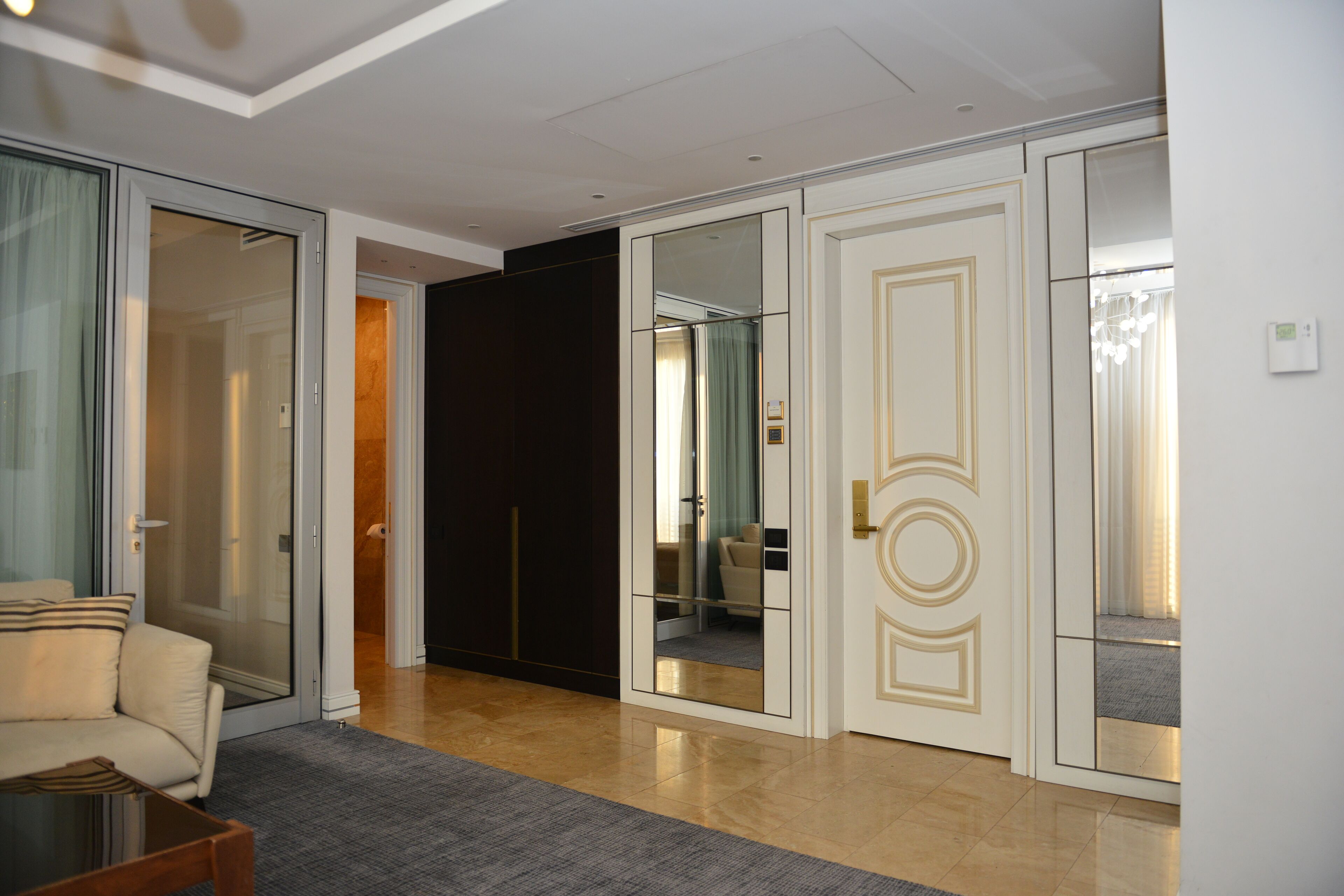 A hotel room with a sliding glass door, a sofa, a small table, and a mirror.