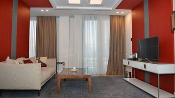 Een moderne hotelkamer met een bank, een bijzettafeltje, een televisie en gordijnen.
