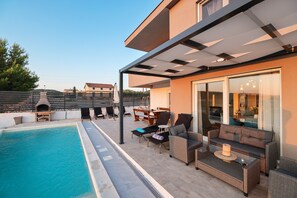 Eine Dachterrasse mit Pool, Sitzgelegenheiten im Freien und einem überdachten Essbereich.