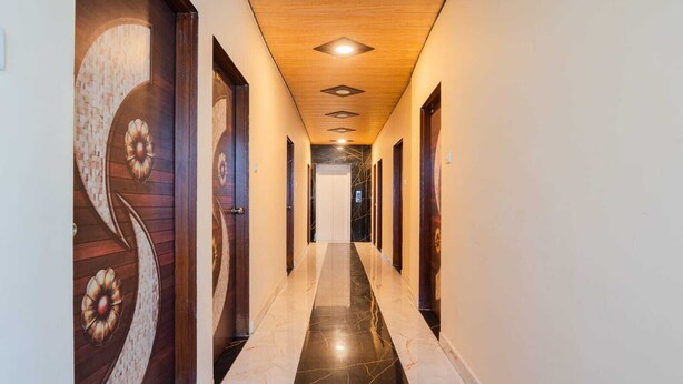 A hallway with wooden doors, a marble floor, and recessed lighting. - Hotel Triple Three By Aditya Inn (Jaipur)