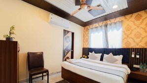 A bedroom with a bed, a chair, an air conditioning unit, and a ceiling fan. - Hotel Triple Three By Aditya Inn (Jaipur)