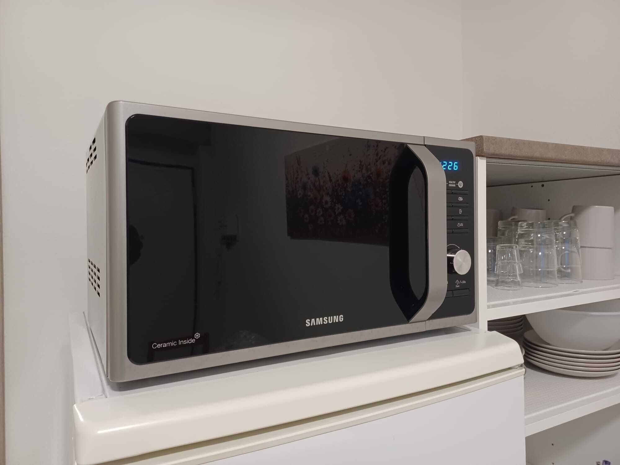Eine Samsung-Mikrowelle mit digitaler Anzeige auf einer weißen Arbeitsplatte.