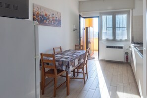 Una cucina compatta con tavolo, sedie e frigorifero.