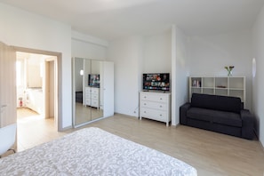 Une chambre à coucher avec un grand lit, une armoire, un canapé, une télévision et une bibliothèque.