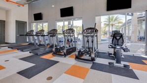 Un gimnasio con cintas de correr, elípticas y una bicicleta estática.