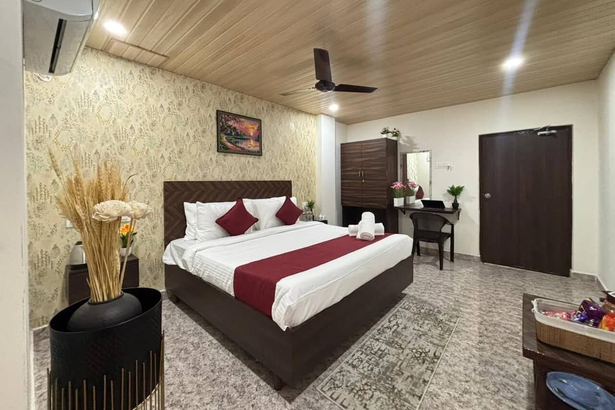 Quarto de hotel com uma cama grande, uma escrivaninha, um guarda-roupa e um ventilador de teto.