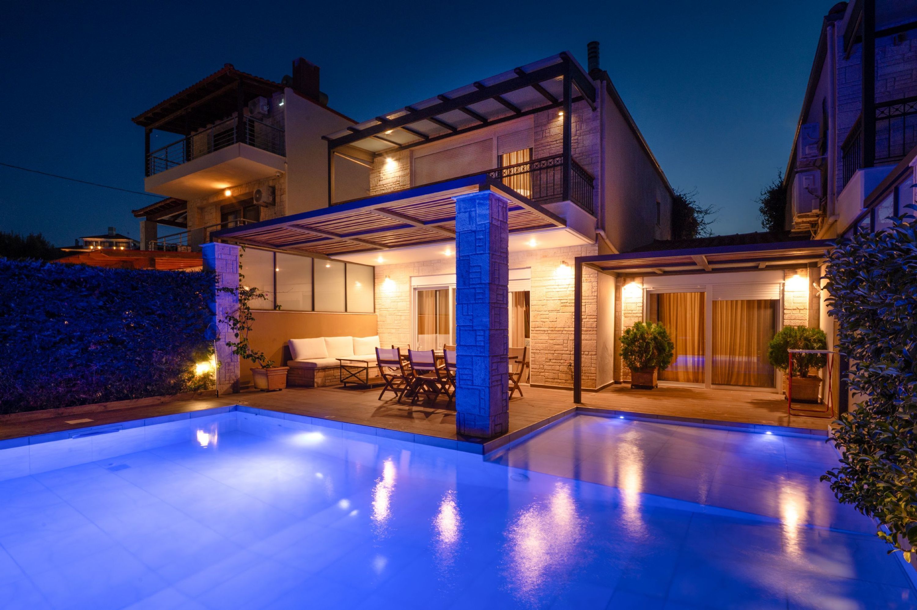 A modern two-story house with a swimming pool, outdoor seating, and a covered patio area.