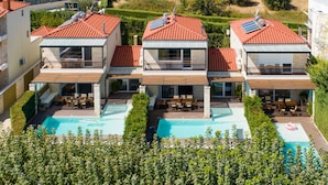 En moderne villa med swimmingpool, solpaneler og en velholdt have.