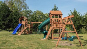 Ein Spielplatz mit Rutsche, Schaukeln und Klettergerüsten.