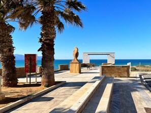 A coastal promenade with palm trees, a sculpture, and a view of the sea. - Anna Penthouse mit Terrasse by Interhome (Balestrate)