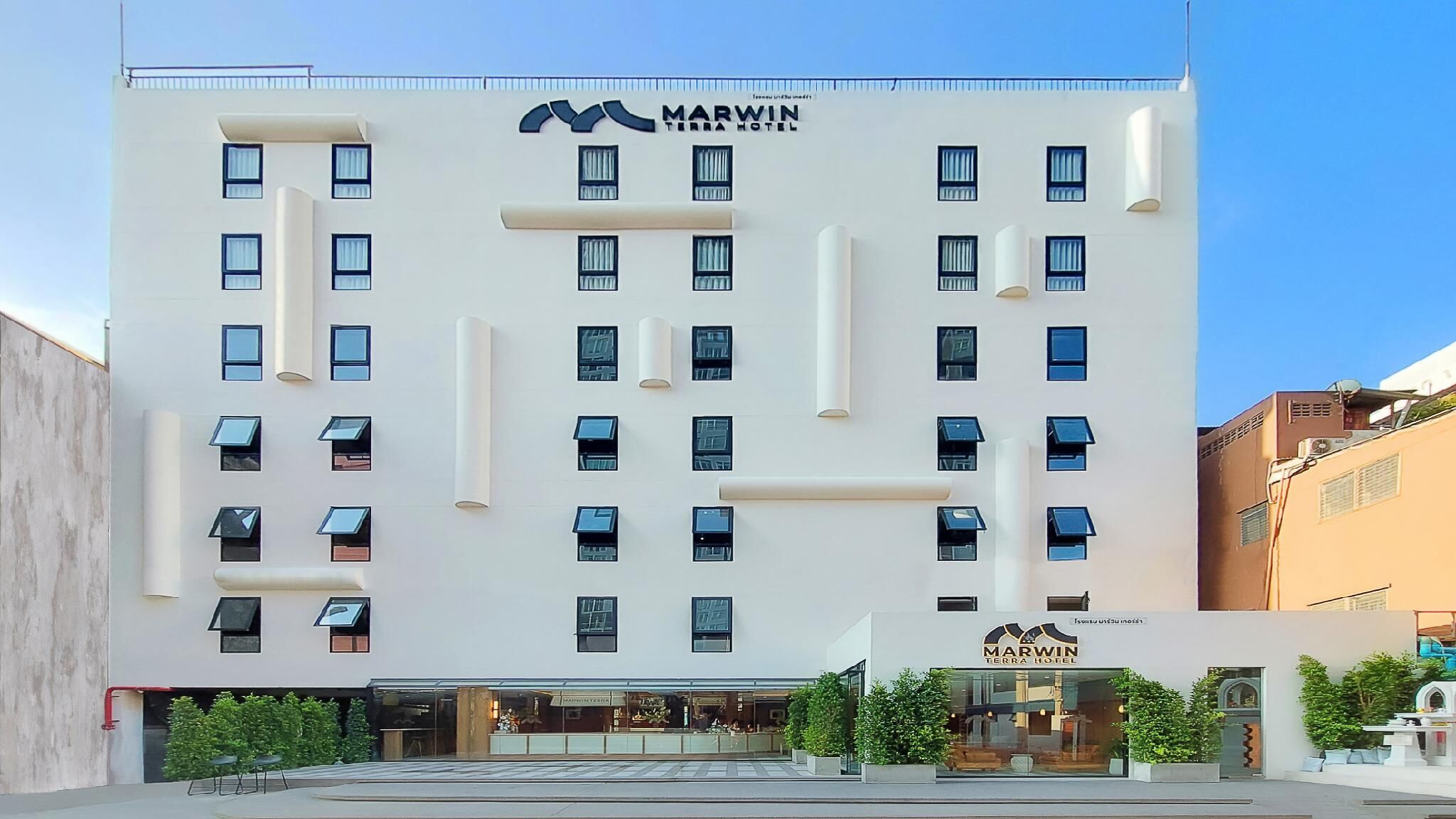 Um hotel moderno com fachada plana, várias janelas e um logotipo bem visível.