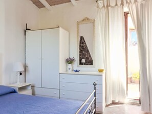Une chambre à coucher comprenant un lit, une armoire, une commode, un miroir et une fenêtre avec des rideaux.