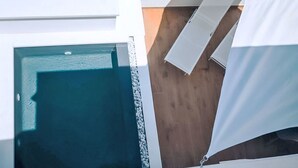 Ein modernes Interieur mit Pool, Holzboden und einem weißen Vorhang.