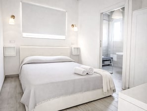 A modern bedroom with a large bed, bedside lamps, and a view of the bathroom. - Villa Ikebana exklusiv in Porto Pino by Interhome (Chia)