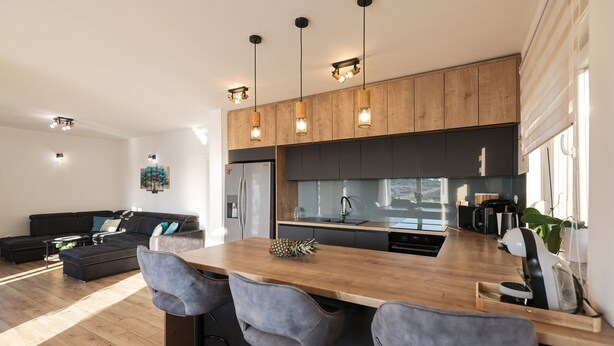 A modern kitchen with wooden cabinets, a central island with bar stools, and pendant lighting. - Villa Carmen Zadarvillas (Sukosan)