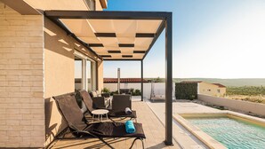 A covered outdoor area with lounge chairs and a pool. - Villa Carmen Zadarvillas (Sukosan)