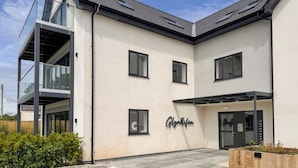 A modern building with a flat roof, large windows, and a nameplate reading "Glunwil." - Glynllifon 6 (Marianglas)