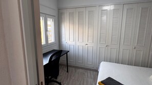 A room with a desk, a chair, and a bed. There are white doors with louvered windows. - Apartment 'Apartamento Martinez Maldonado' with Wi-Fi and Air Conditioning (Málaga)
