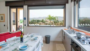Een eetruimte met een tafel voor vier personen, uitzicht op het landschap en een keuken met moderne apparatuur.