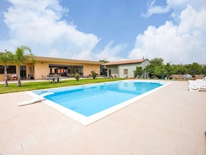A swimming pool with lounge chairs, a patio area, and a building with a tiled roof. - Villa Germano with Pool, Mountain View, Wi-Fi & Air Conditioning (Solarino)
